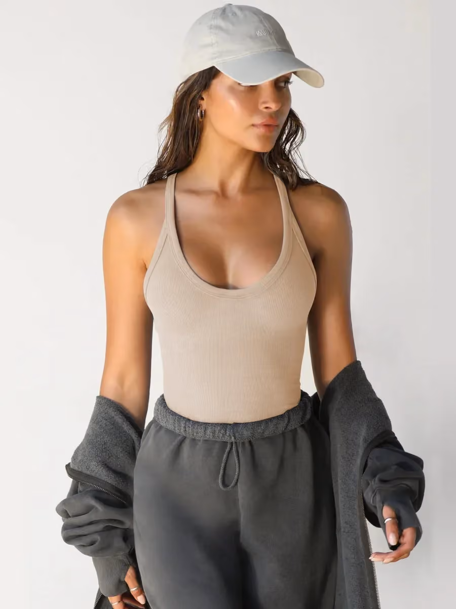woman in a khaki ribbed v neck workout tank top with joggers and a cap